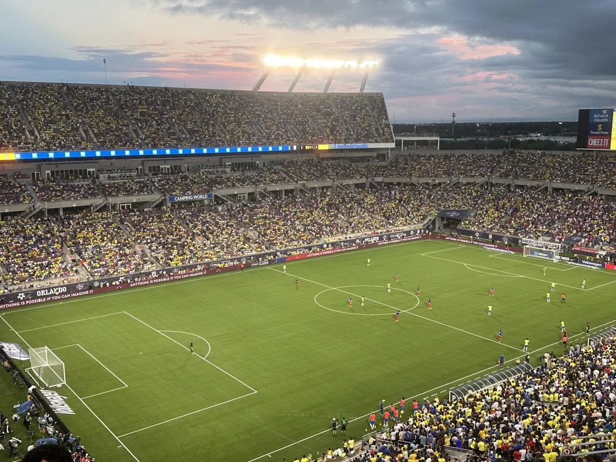 大型足球体育场全景，绿茵场在灯光下格外耀眼